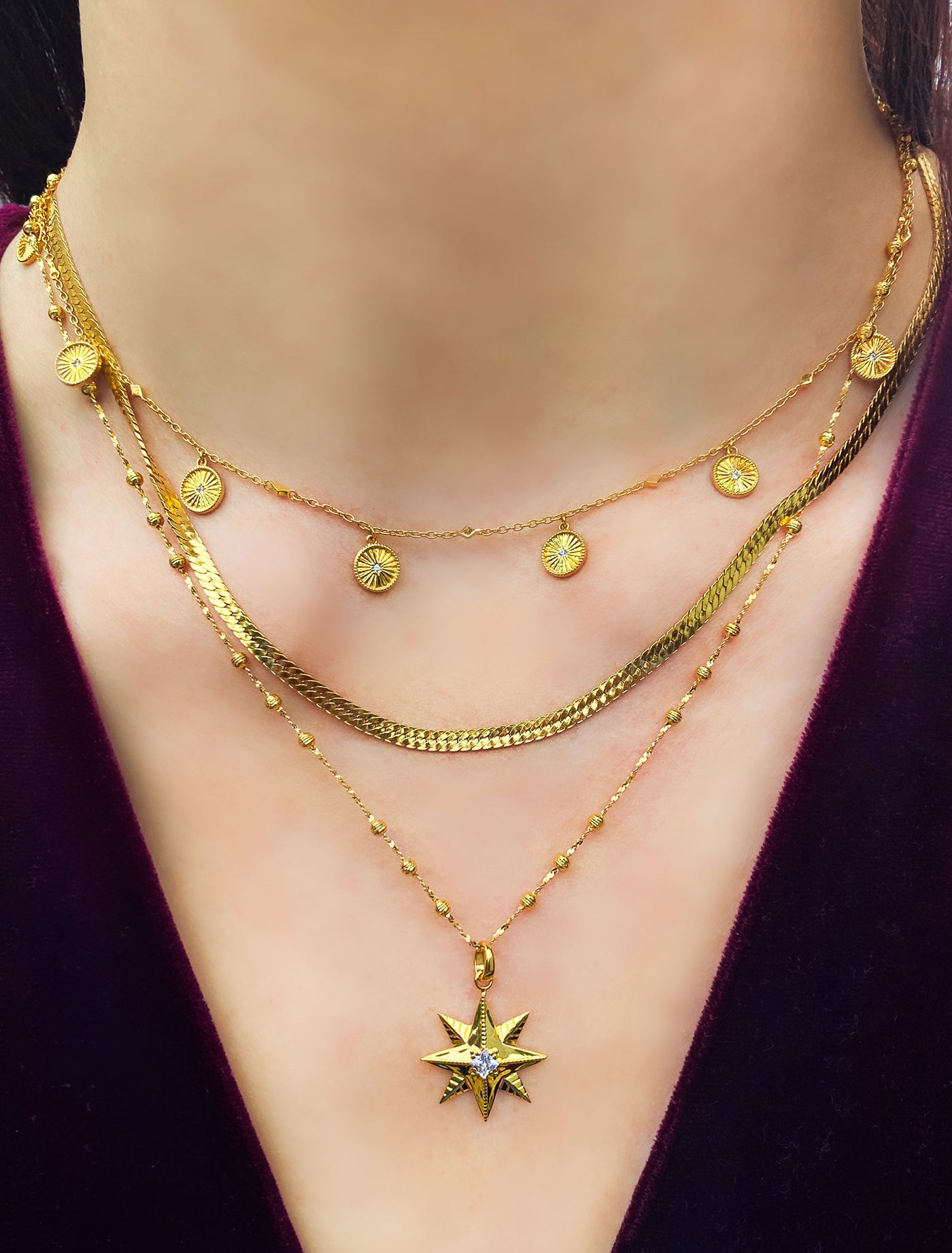 Model wearing gold plated sterling silver star necklace, layered with snake chain and engraved sun choker with cz crystals