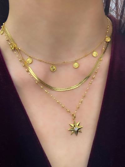 Model wearing gold plated sterling silver star necklace, layered with snake chain and engraved sun choker with cz crystals