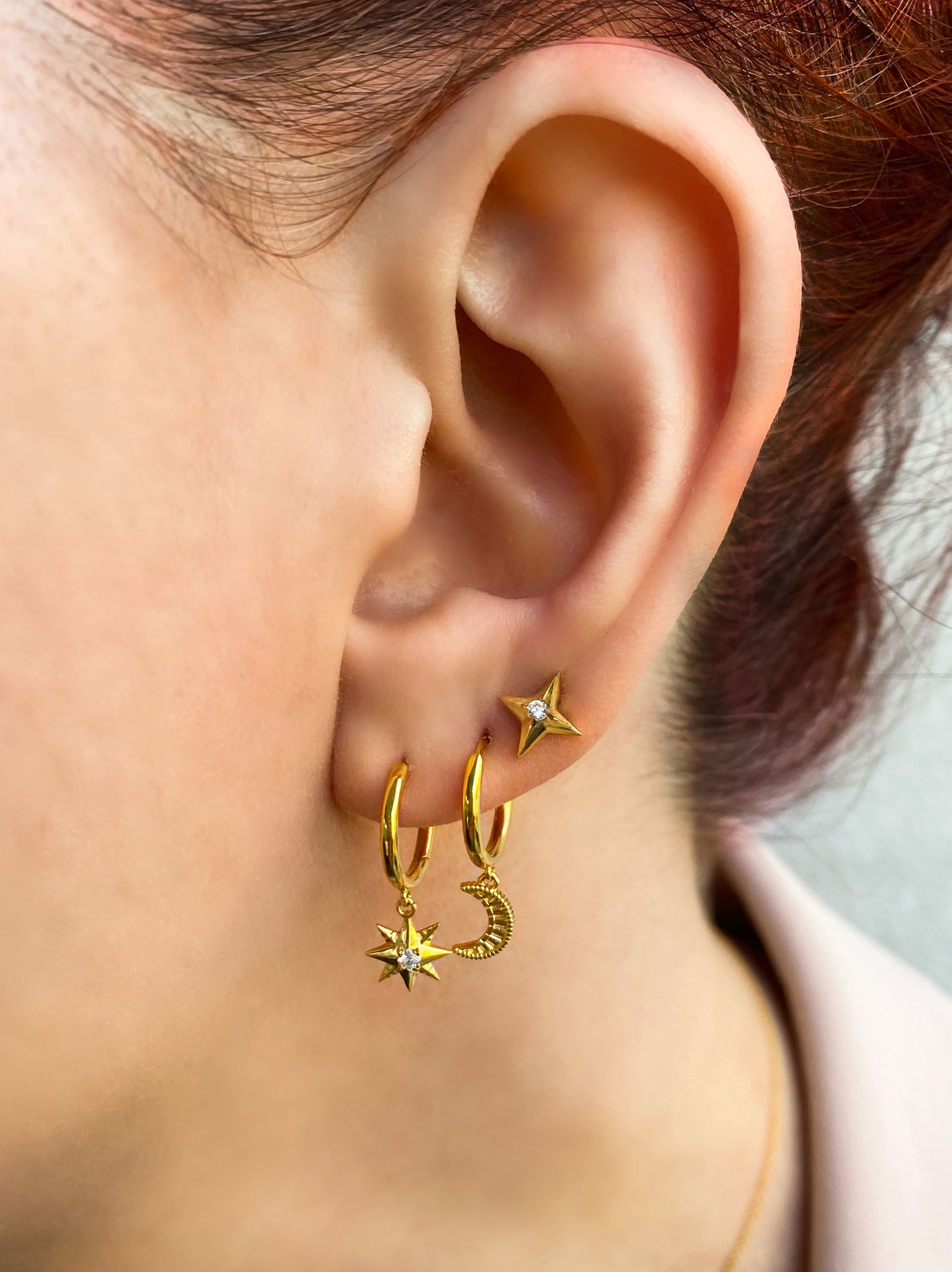 Model wearing mini gold star and moon huggie hoops with cz star earring