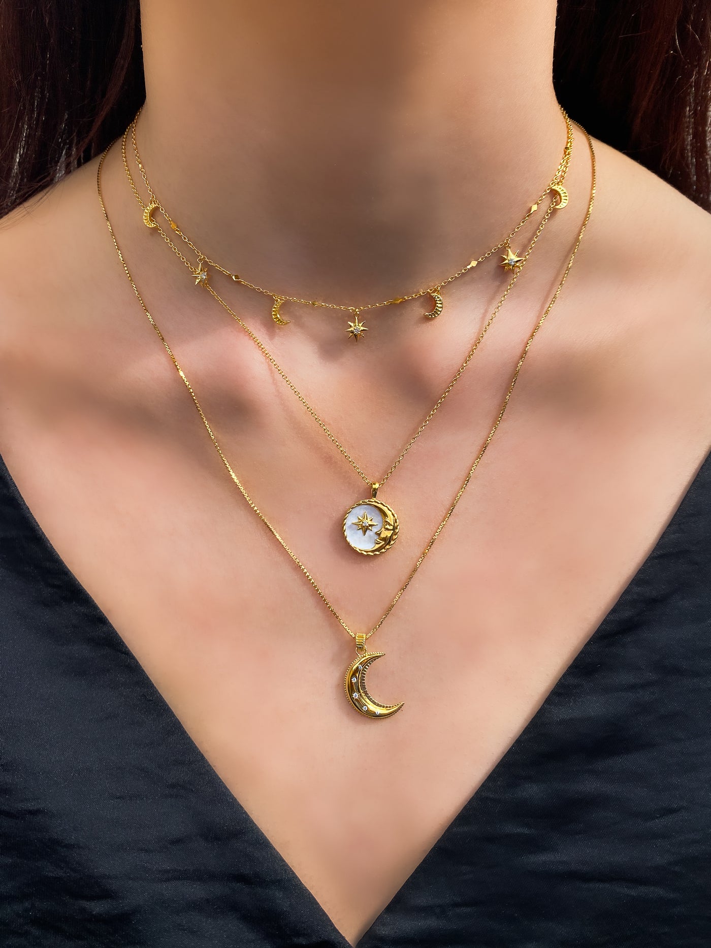 Model wearing gold moon and star choker with CZ crystals, layered with engraved mother of pearl moon, coin pendant and moon necklace 