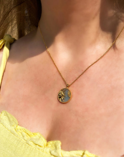 Model wearing gold engraved sun coin pendant on semiprecious amazonite base