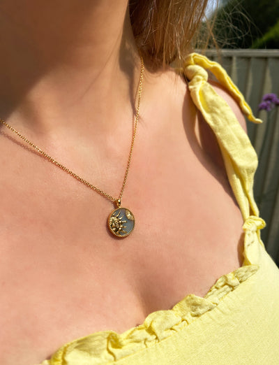 Model wearing gold engraved sun coin pendant on semiprecious amazonite base