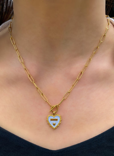 Model wearing gold plated brass heart pendant on chunky chain with light blue enamel base, engraved wording and engraved edging